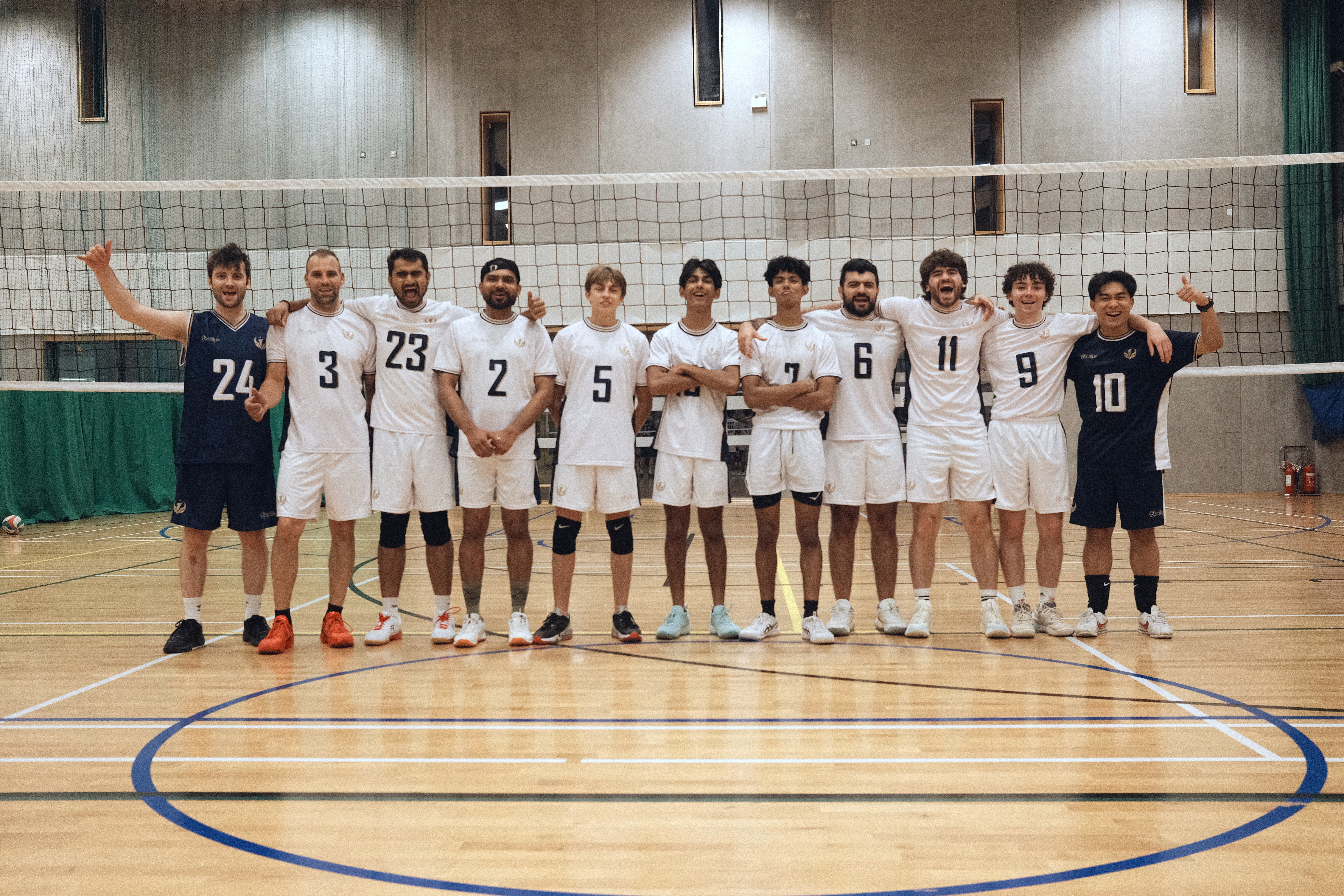 Celestials Men’s Regional squad standing together on the volleyball court in their white and navy kits.